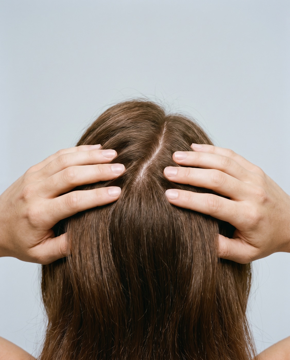 A person parting their hair to look at the scalp