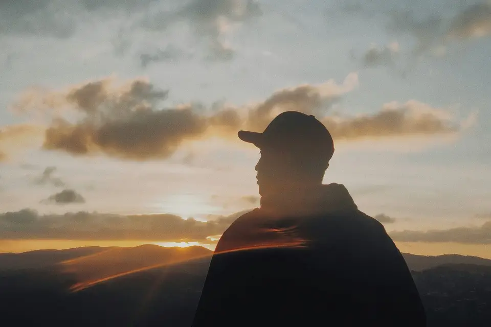 A person outdoors at sunset, wrapped against the evening air