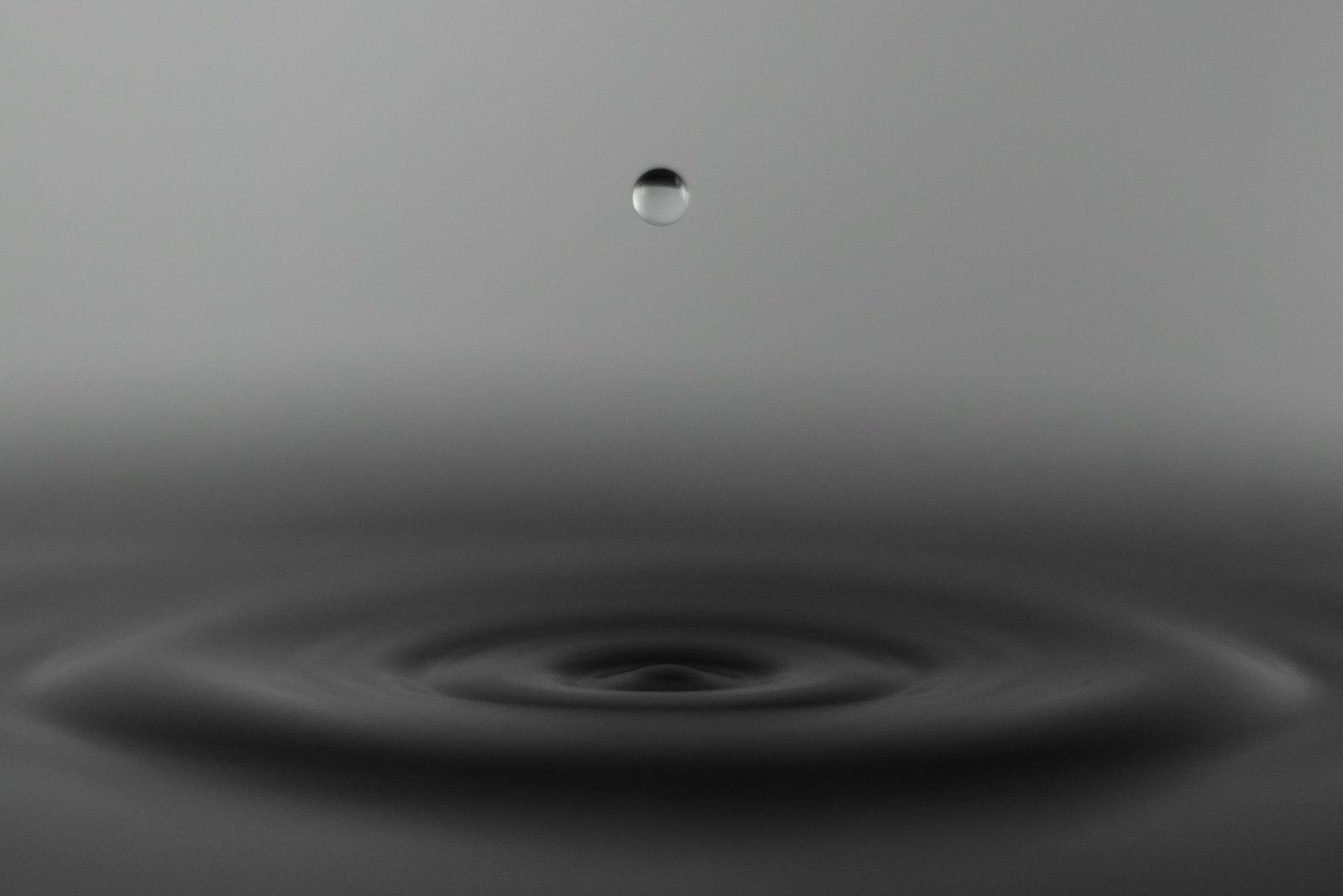 A single water droplet suspended above fading concentric ripples, a visual analogy for tirzepatide clearing the system