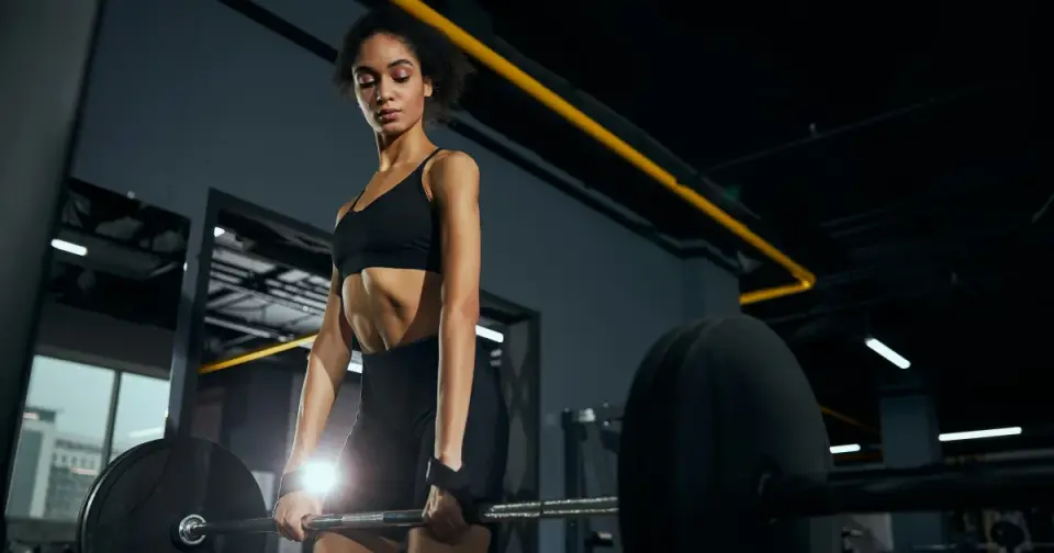 A woman lifting a barbell in a gym, representing steady, natural energy and strength