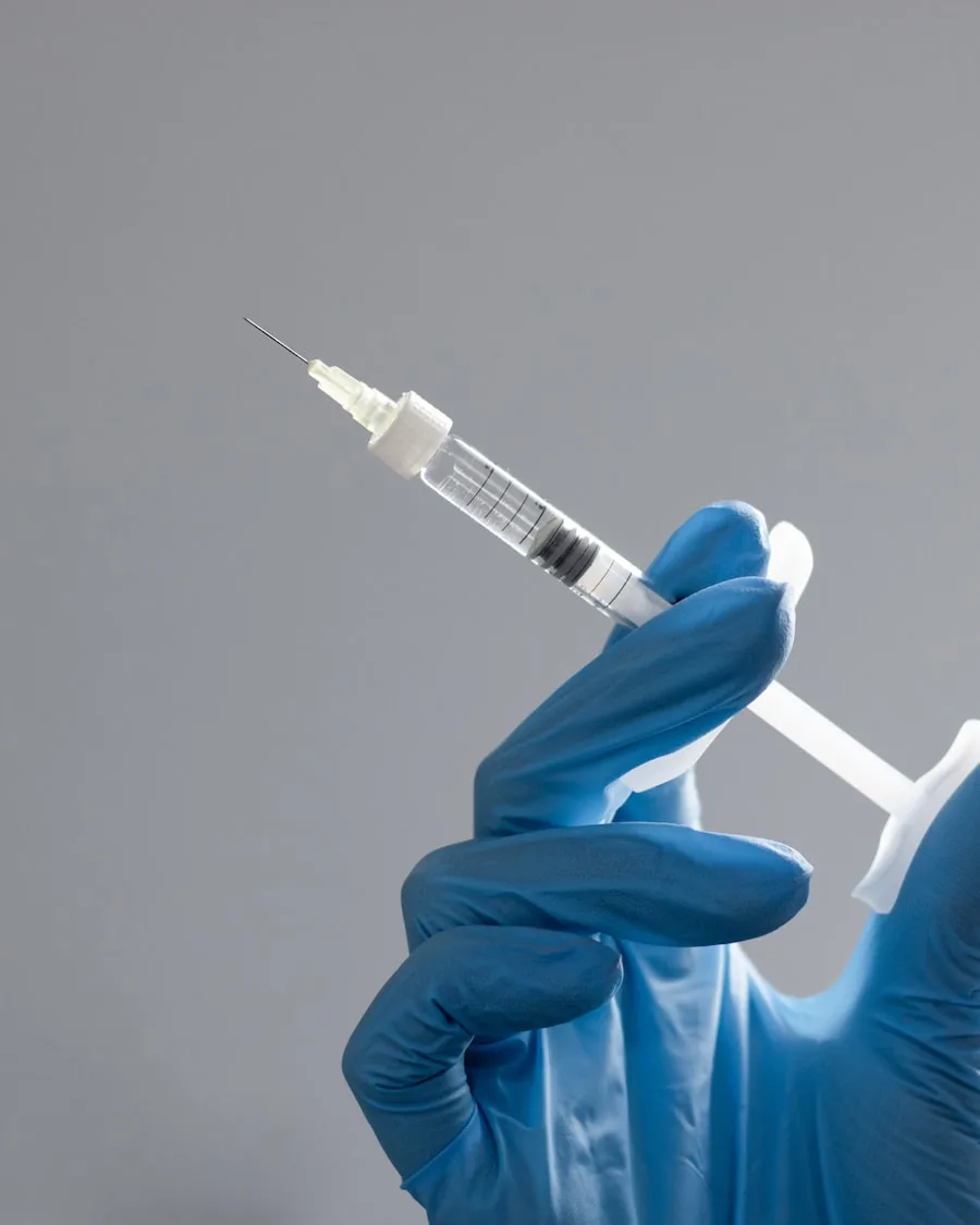 A gloved clinician's hand holding a prepared syringe in a clean clinical setting, representing physician-prescribed sermorelin dosing.