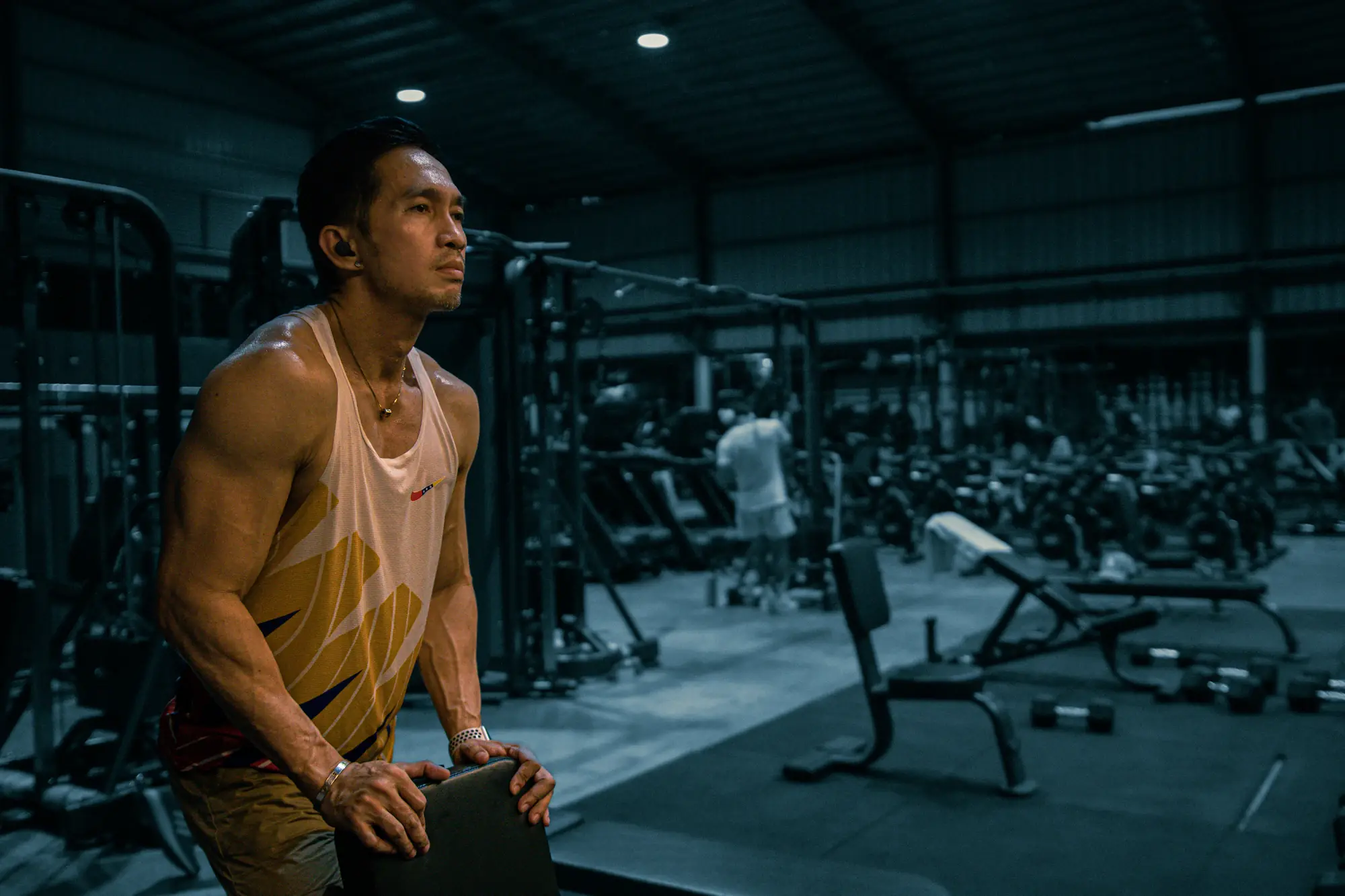 A lean, focused man resting between sets in a gym